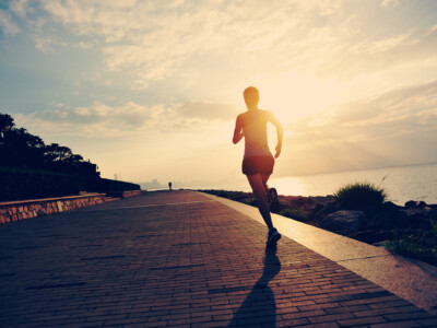 Runner athlete running at seaside. woman fitness silhouette sunrise jogging workout wellness concept.